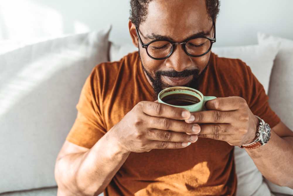 Man enjoying coffee on a cozy couch with soft pillows at Colonial Park in Indianapolis, Indiana