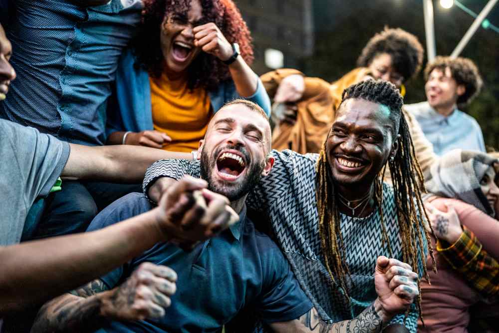 Group of friends laughing and celebrating together in a lively outdoor setting at Colonial Park in Indianapolis, Indiana
