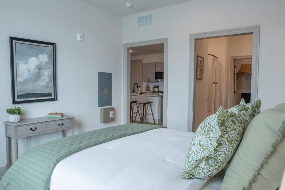 Bedroom with white bedding and wall art at The Flats at Crosspointe in Columbia, South Carolina