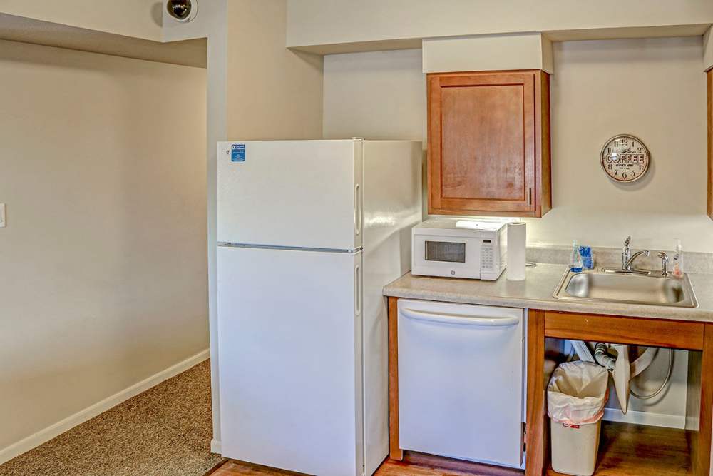 Bright kitchen with white appliances, wood-style flooring, and wooden cabinets at Alston Park in Cincinnati, Ohio