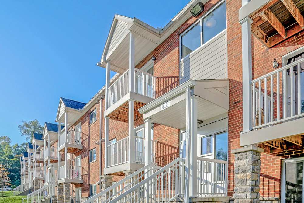 Brick apartment buildings with balconies and gated entrance surrounded by greenery at Alston Park in Cincinnati, Ohio