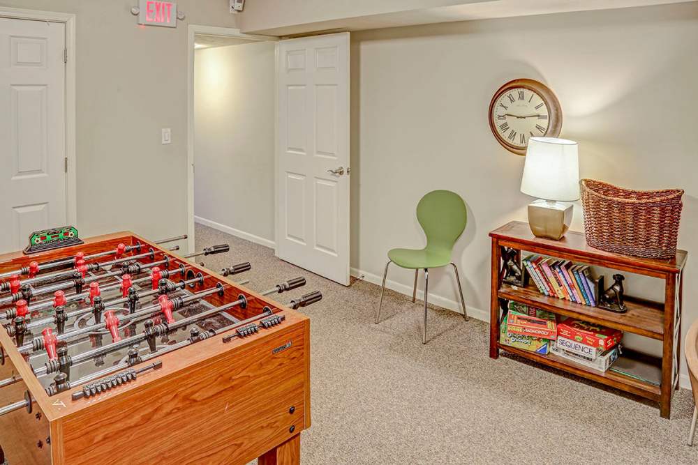 Game room with foosball table, green chair, bookshelf, and lamp in cozy setting at Alston Park in Cincinnati, Ohio
