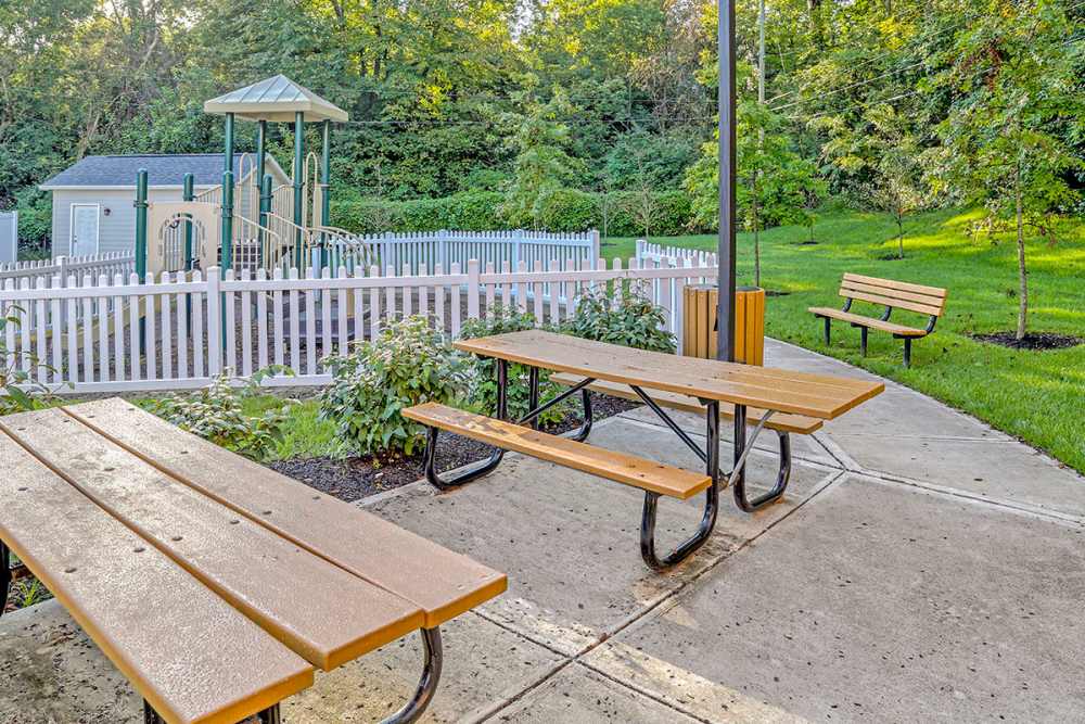 Picnic tables near a fenced playground surrounded at Alston Park in Cincinnati, Ohio