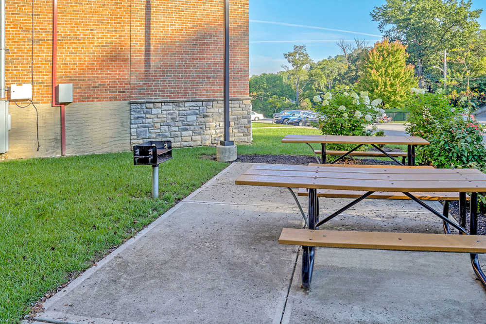 Outdoor picnic area with benches, grill, and landscaped greenery at Alston Park in Cincinnati, Ohio