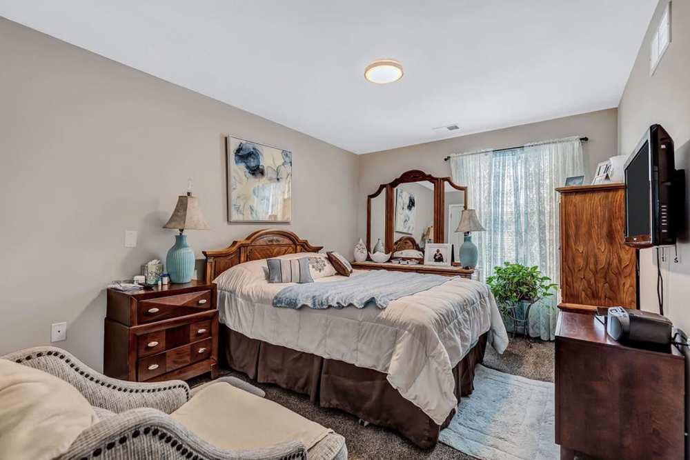 Bedroom with comfortable bed and a large window at Audubon Crossing Senior Community in Dayton, Ohio 