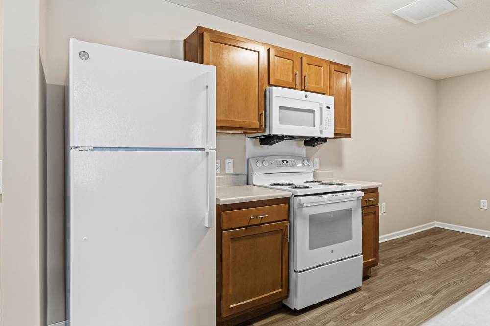 Modern kitchen with granite countertops, stainless steel appliances, and wood-style flooring at Granville Woods Lofts in Columbus, Ohio