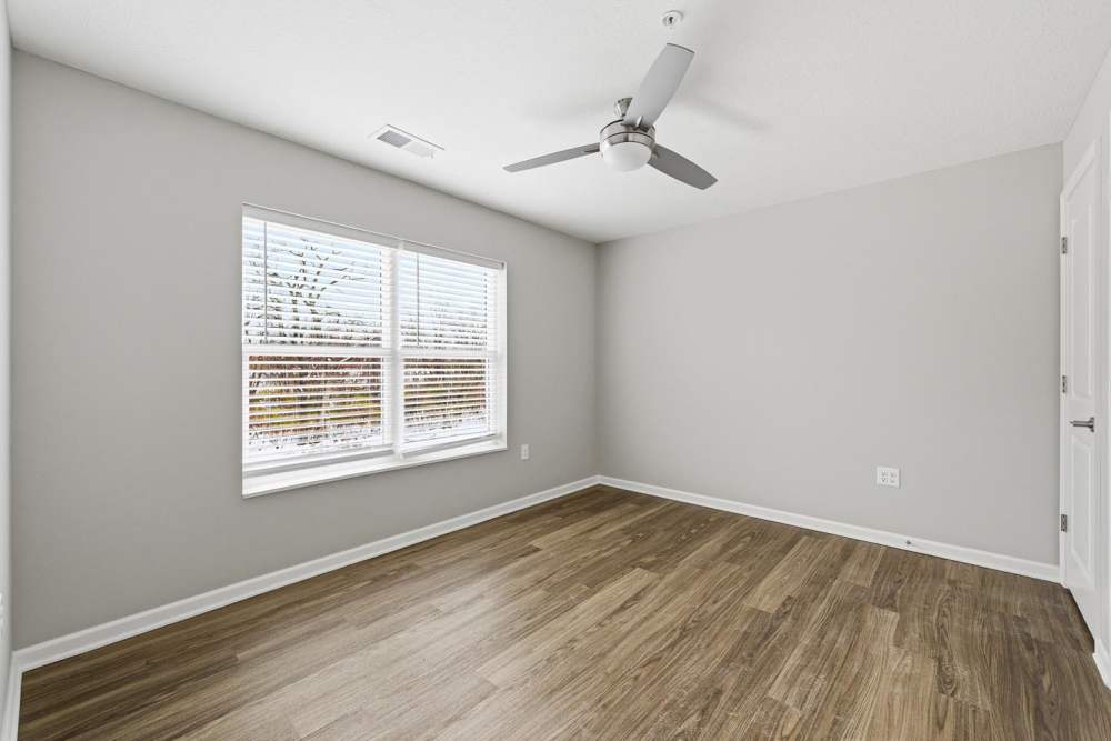 Bright room with wood-style flooring, ceiling fan, and large windows at Granville Woods Lofts in Columbus, Ohio