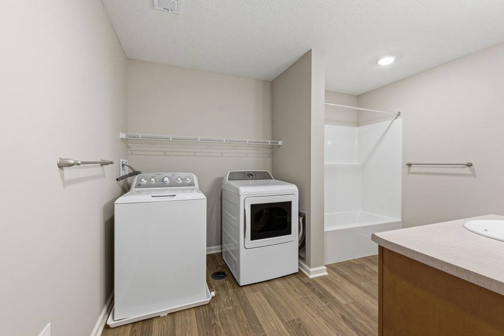 Laundry room with washer and dryer, wood-style flooring, and a shower stall at Granville Woods Lofts in Columbus, Ohio
