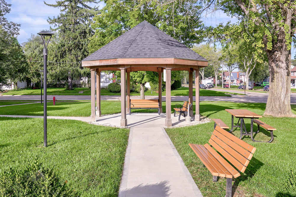 Gazebo with wooden benches and picnic tables surrounded by green grass and trees at Hayden House in Springfield, Ohio