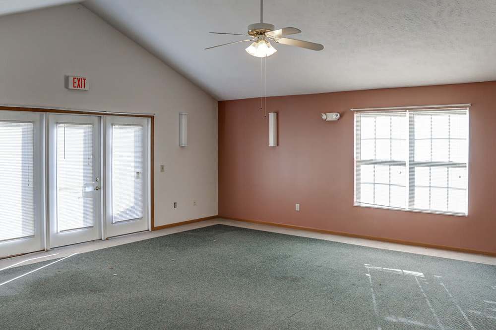 Well-lit clubhouse with a ceiling fan and large windows at Ivy Glen in Washington Court House, Ohio 
