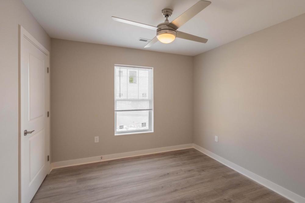 Bright bedroom with wood-style flooring and ceiling fan, featuring a window with natural light at Sells Greene in Lancaster, Ohio