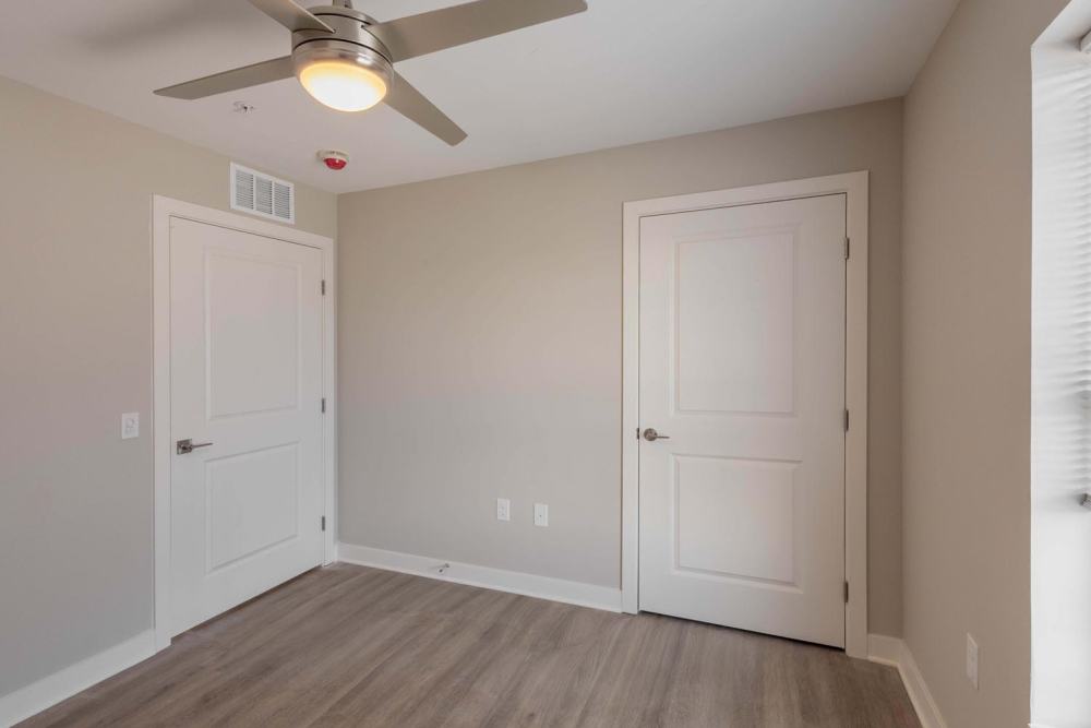 Bedroom with ceiling fan and featuring two white doors and neutral walls at Sells Greene in Lancaster, Ohio