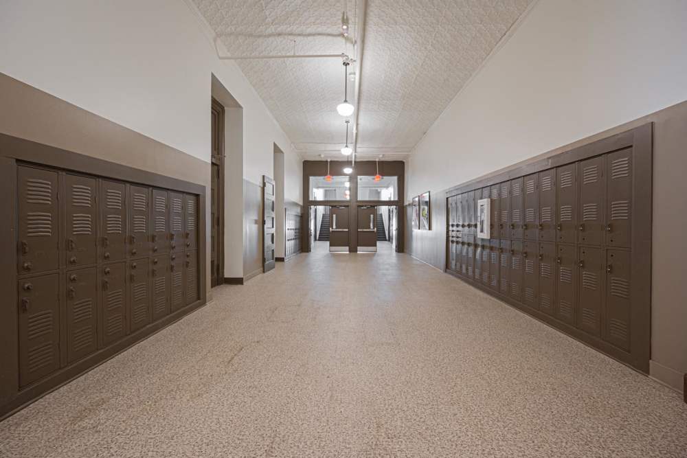 Long hallway with brown lockers, high ceilings, and bright overhead lights at Starling Yard in Columbus, Ohio
