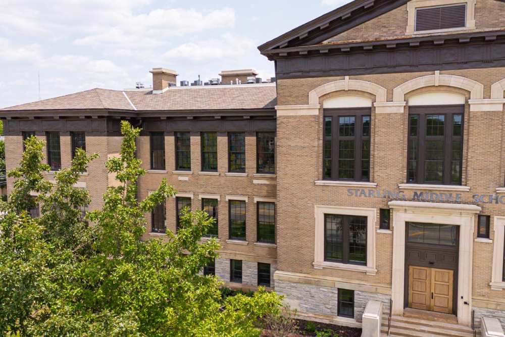 Building exterior with large windows and brick facade surrounded by trees and greenery at Starling Yard in Columbus, Ohio