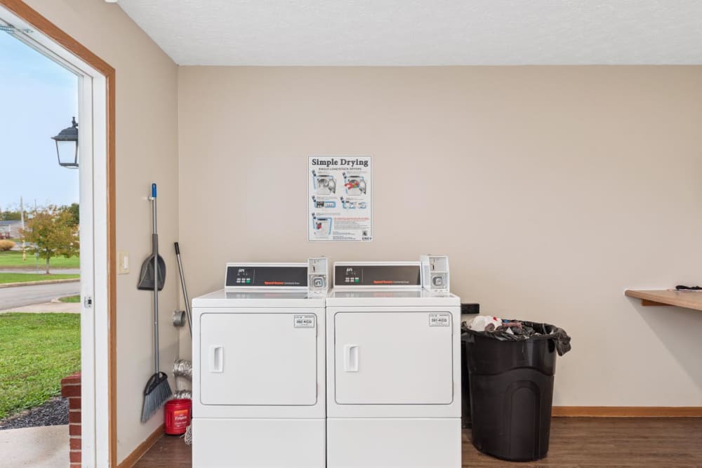 Laundry room with two white machines, broom and trash can at Webster Glen in Peebles, Ohio
