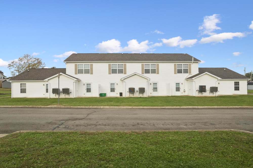 Two-story apartment building with green lawn and air conditioning units outside at Webster Glen in Peebles, Ohio