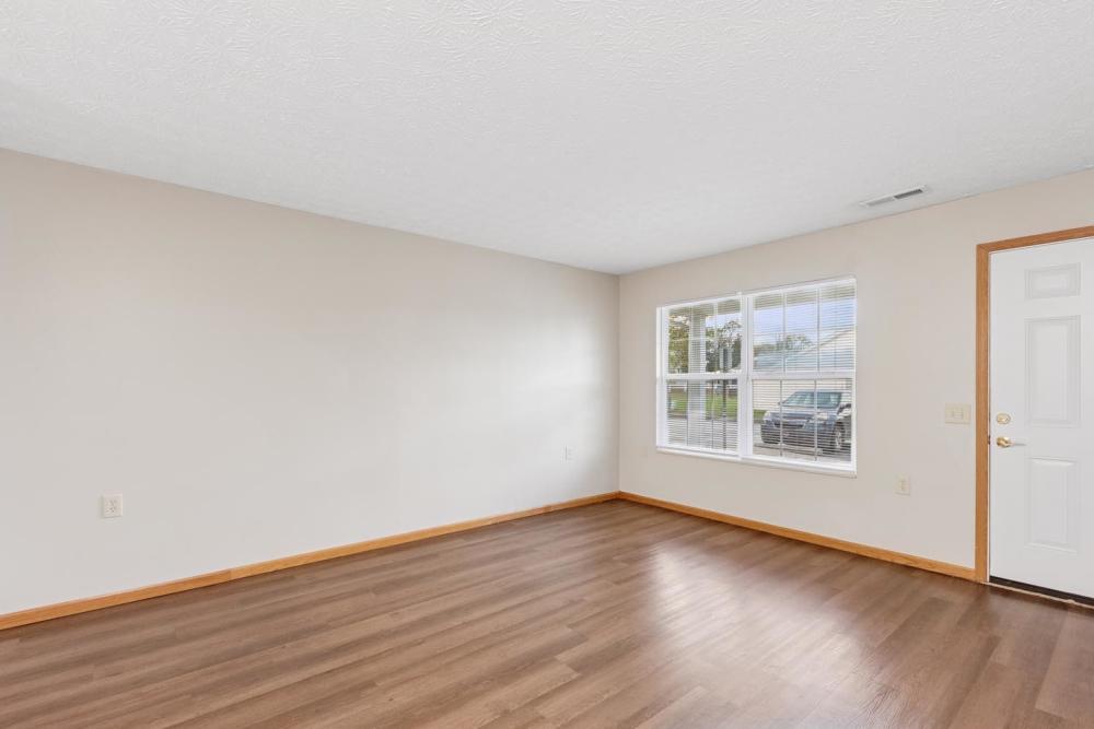Spacious living area with wood-style flooring and large windows for natural light at Webster Glen in Peebles, Ohio