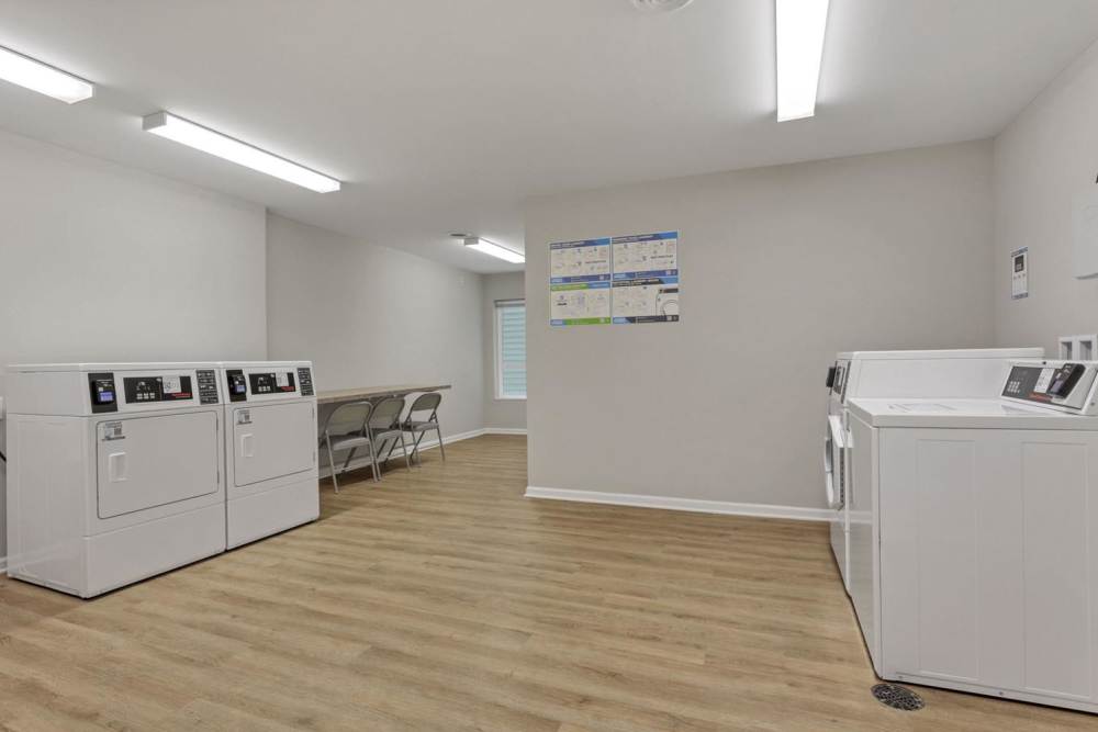 Laundry machines with folding table and chairs at McKinley Manor in Columbus, Ohio