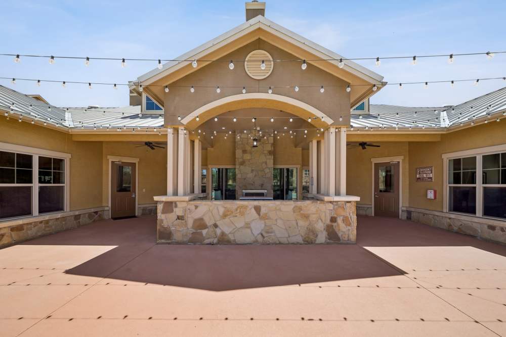 String lights and patio area with clubhouse building in background at Blue Ridge in Midland, Texas