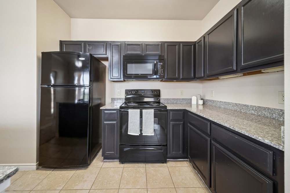 Dark wooden cabinets and black appliances in kitchen at Blue Ridge in Midland, Texas
