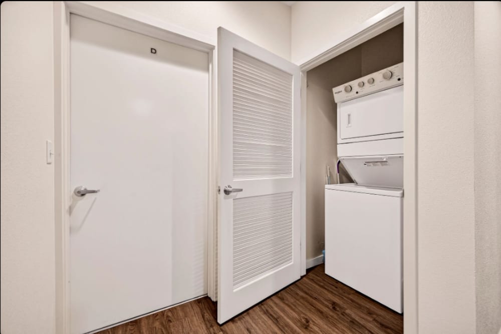 Laundry: Stacked washer and dryer inside a hallway closet with louvered door and adjacent interior door at Cedar Flats in Chico, California  