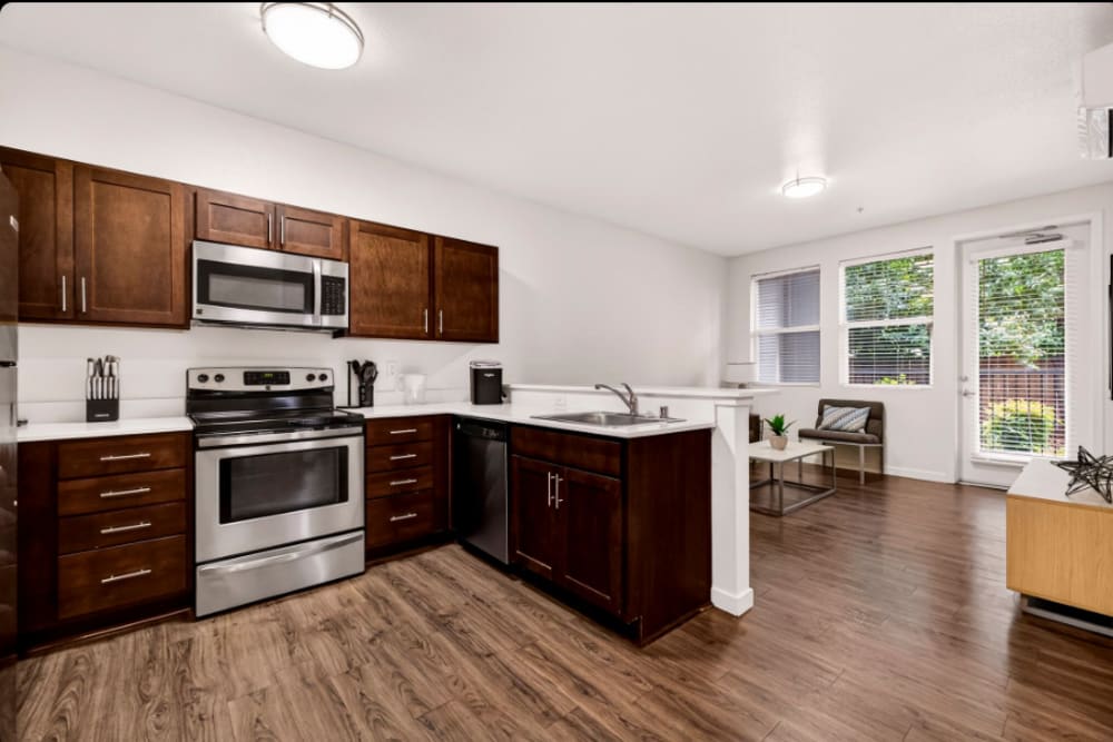 Kitchen to living: Open kitchen flowing into living area with island sink, windows, and seating area at Cedar Flats in Chico, California  