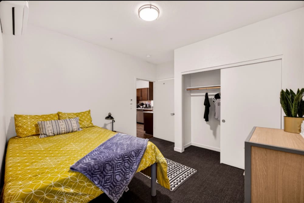 Bedroom: Bedroom with full-size bed, patterned bedding, open closet, dresser, and doorway to kitchen at Cedar Flats in Chico, California  