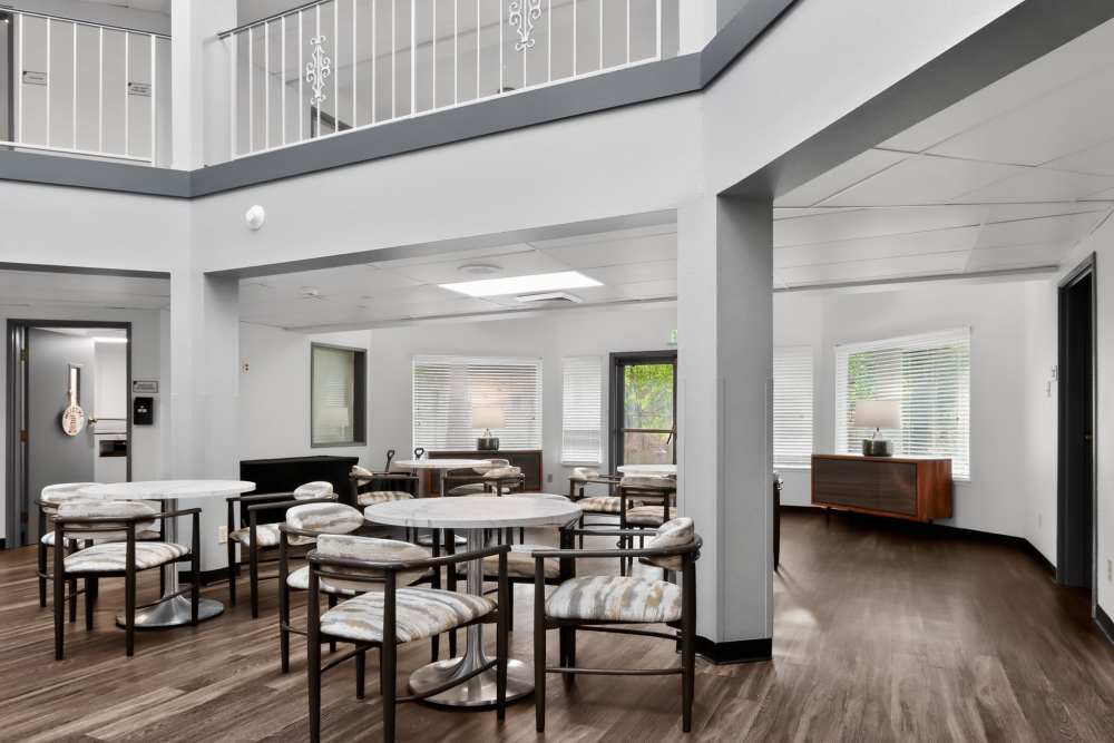 Dining area with round tables, cushioned chairs, and open view to adjacent rooms at Whealdon Estates by Barclay House in Baton Rouge, Louisiana  