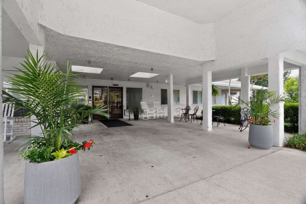 Covered outdoor entry with concrete floor, potted plants, seating, and glass doors at Whealdon Estates by Barclay House in Baton Rouge, Louisiana  