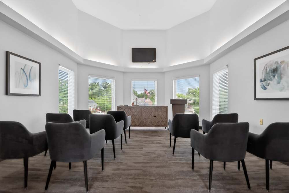 Bright meeting room with rows of gray chairs facing a podium, TV screen, and large windows at Whealdon Estates by Barclay House in Baton Rouge, Louisiana  