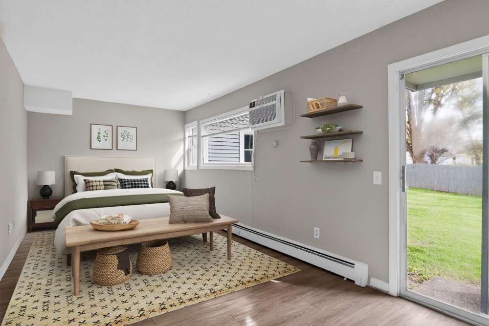 Modern bedroom with a white dresser, decorative vase, and cozy green blanket on the bed at The Flats at Talcott in Weatogue, Connecticut
