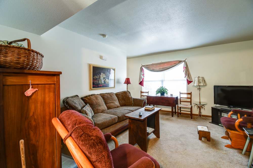 Cozy living room with plush seating, wooden furniture, and natural light from large window at Catawba Club in Berkeley Springs, West Virginia