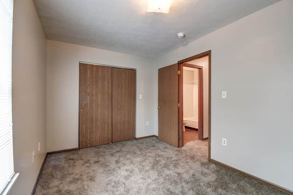 Cozy bedroom with carpeted flooring and double closet doors, natural light from window at Cedar Glen I in Morgantown, West Virginia