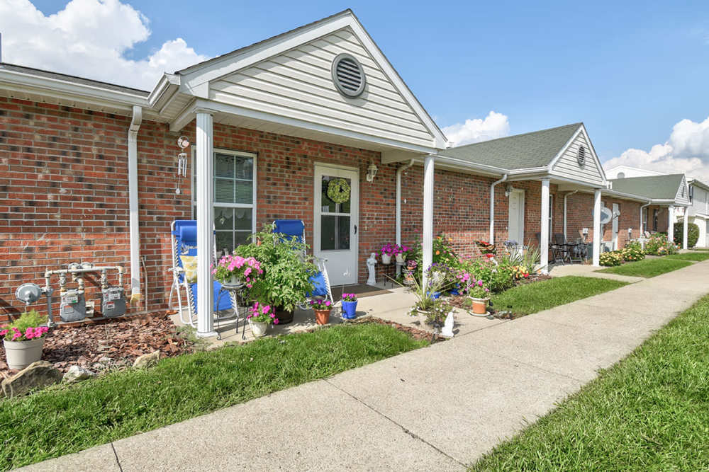 Charming apartment community with flower-filled patios and well-maintained walkways under a clear blue sky at Cedar Glen I in Morgantown, West Virginia