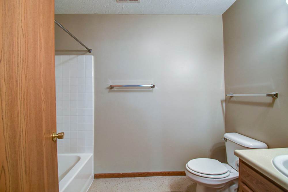 Spacious bathroom with a tub, shower rod, and neutral-colored walls at Oakmont Greene II in Mount Hope, West Virginia