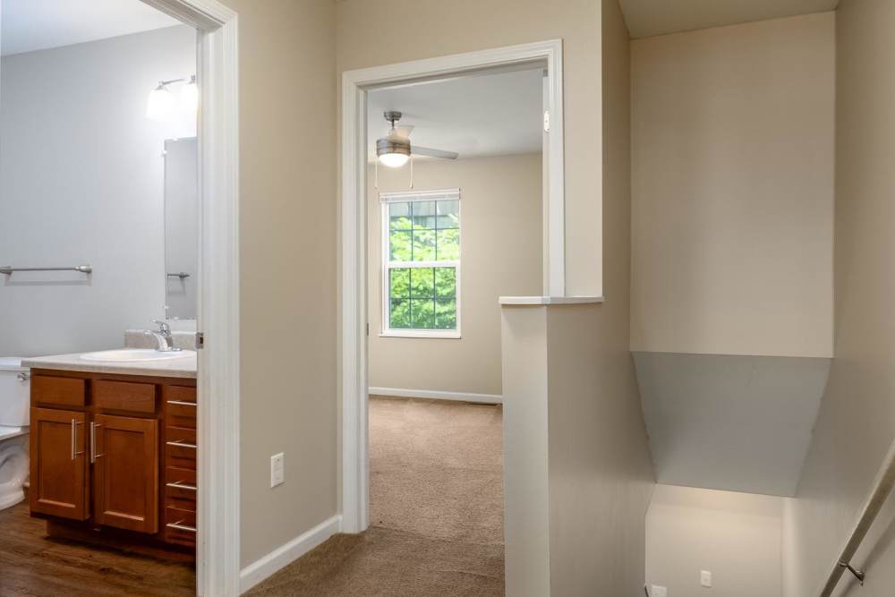 Bright hallway leading to a carpeted bedroom and bathroom with wooden cabinetry at Labelle Greene III in Wheeling, West Virginia
