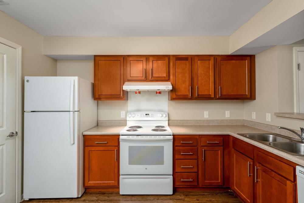 Modern kitchen with wood-style flooring, stainless steel appliances, and warm wood cabinets at Labelle Greene III in Wheeling, West Virginia