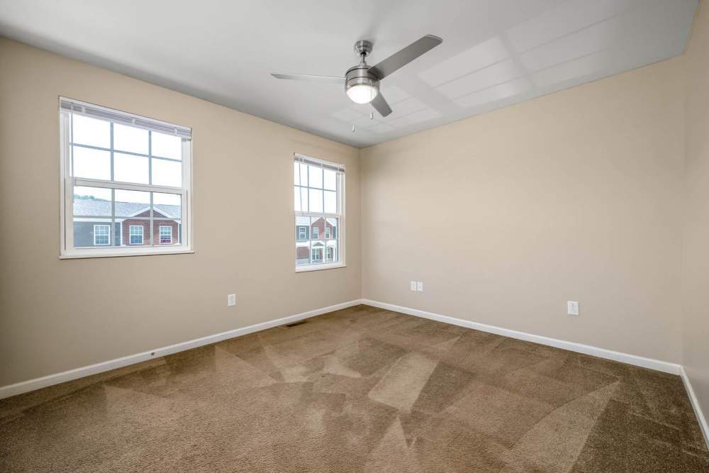 Empty bedroom with carpeted flooring, ceiling fan, and two windows providing natural light at Labelle Greene III in Wheeling, West Virginia