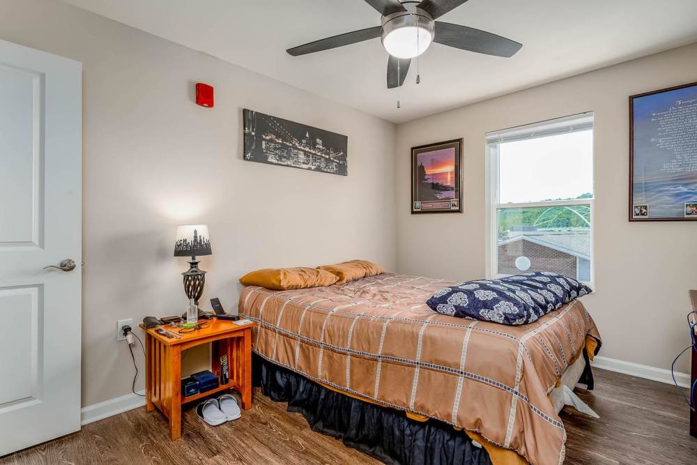 Cozy bedroom with wood-style flooring, ceiling fan, and natural light from window at Labelle Greene IV in Wheeling, West Virginia