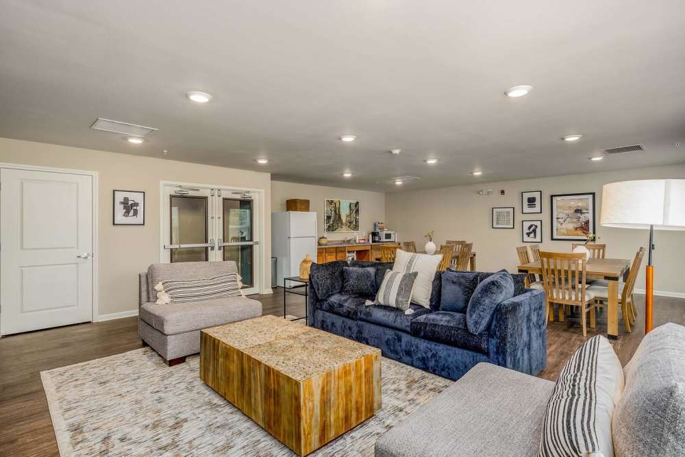Spacious community lounge with wood-style flooring, comfortable seating, and dining area with wooden table at Labelle Greene IV in Wheeling, West Virginia