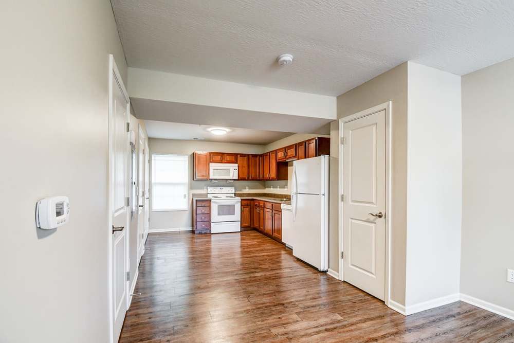 Open layout kitchen with wood-style flooring, stainless steel appliances, and granite countertops at Owens Greene in Wheeling, West Virginia