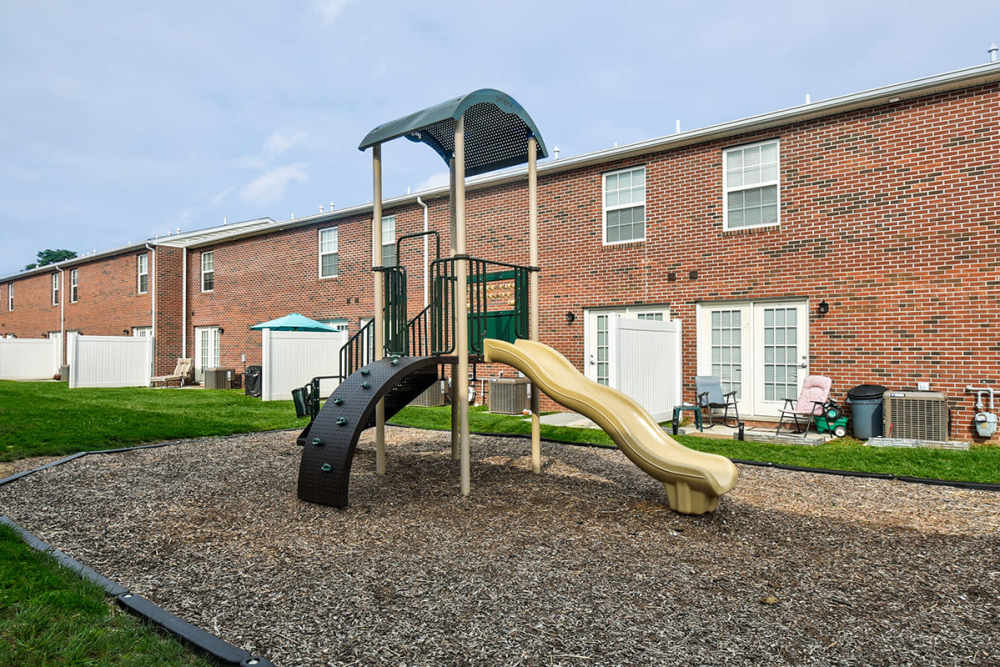 Playground with slide and climbing structure surrounded by grass and brick apartment buildings at Terrapin Park in Parkersburg, West Virginia