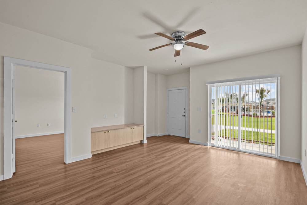 Spacious living area with wood-style flooring and ceiling fan, large windows overlooking outdoor space at Springwood at Aliana in Richmond, Texas