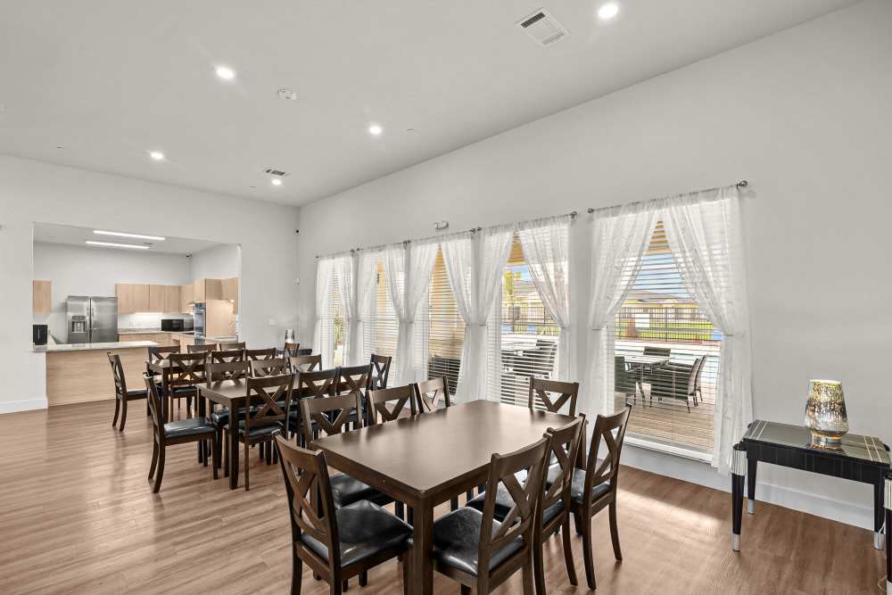 Bright community dining area with wood-style flooring and large windows overlooking the patio at Springwood at Aliana in Richmond, Texas
