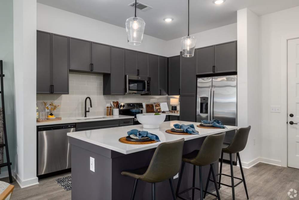 Stylish kitchen with island seating, dark cabinets, and stainless appliances at The Millwright in Cornelius, North Carolina