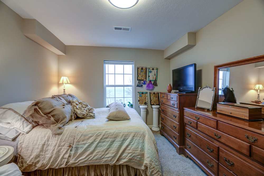 Bedroom with a window and wooden cabinets at Willoughbeach Terrace Senior Living in Willowick, Ohio 