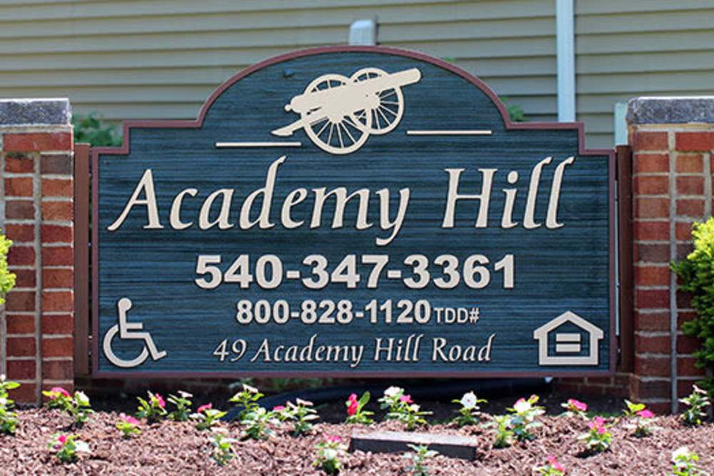Sign for Academy Hill with contact information and accessible symbol surrounded by colorful flowers at Academy Hill in Warrenton, Virginia