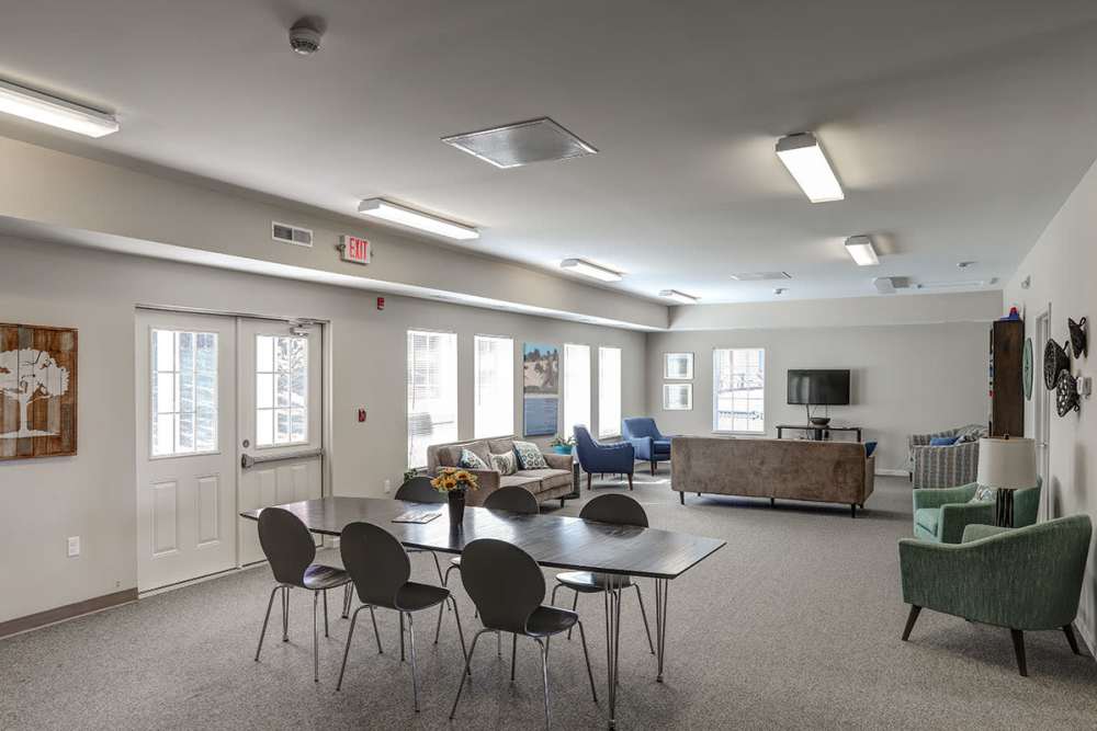 Bright community lounge with seating areas, dining table, and large windows for natural light at Brookside Commons in Traverse City, Michigan