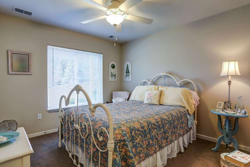Cozy bedroom with floral bedding, ceiling fan, and natural light from window at Brookside Commons in Traverse City, Michigan