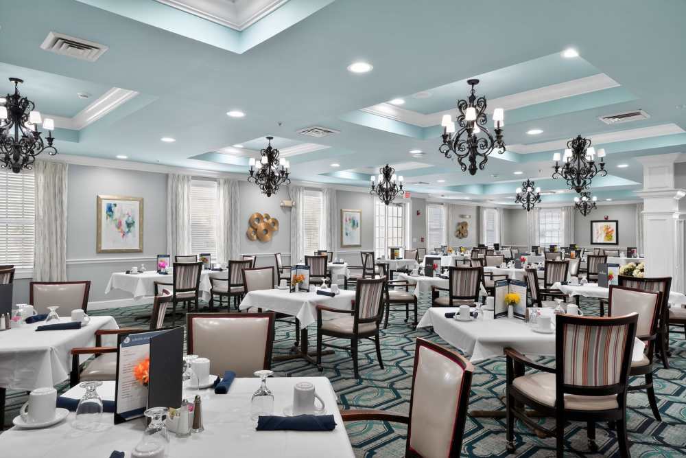 Lively and elegantly furnished common room with chandeliers and table seating at The Barclay at Vero Beach in Vero Beach, Florida